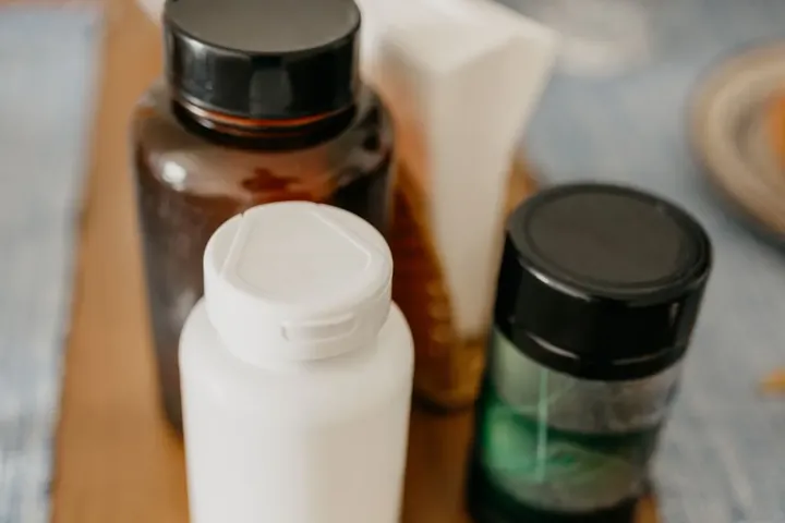 Supplement bottles and capsules lined up on a wooden kitchen table
